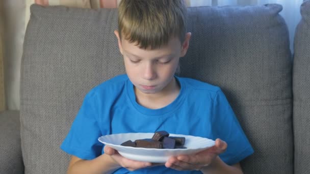 Niño con carácter. Adolescente mira dulces y los huele. Concepto de alimentación poco saludable . — Vídeo de stock