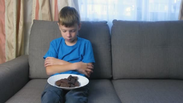 Jongen met karakter. Tiener kijkt snoepjes. Concept van ongezond eten. — Stockvideo