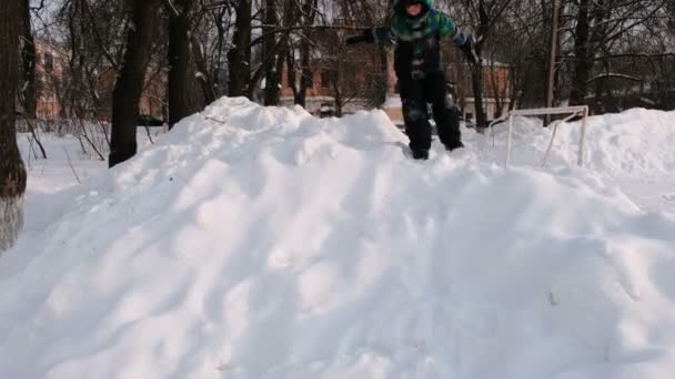 Pojke leker i snön. Glidande från de snötäckta bergen uppochner. — Stockvideo