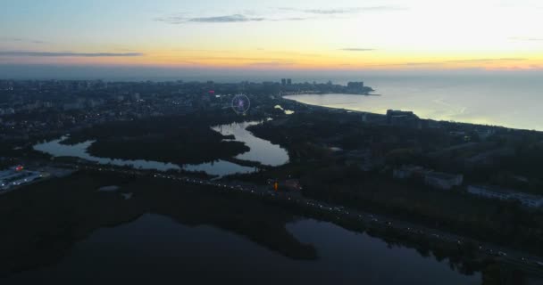 Hermosa vista aérea nocturna de la ciudad costera con el río que fluye en el mar en la puesta del sol . — Vídeos de Stock