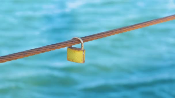 Rusty Padlock hanging on a iron wire on the sea water background. — Stock Video