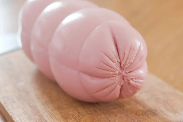 Big boiled sausage on wooden Board on the table. Close-up view. — Stock Photo, Image