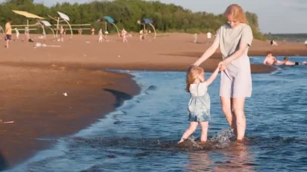 Mamá y niña jugando en la playa del río al atardecer y nadar . — Vídeos de Stock