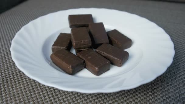 Schokoladenbonbons auf einem weißen Teller. Konzept der ungesunden Ernährung. — Stockvideo