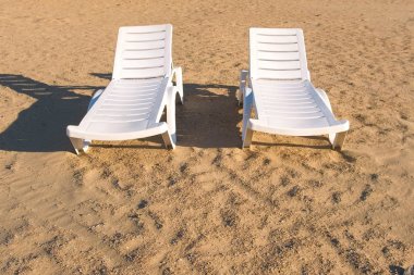 Yaz kum plajında iki sunlongers.