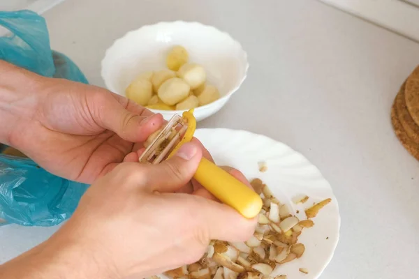 Mans hands is peeling potato with yellow peeler. — Stock Photo, Image