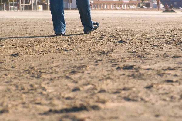 黒の靴とジーンズ レディース フィートの砂浜のビーチに行く. — ストック写真