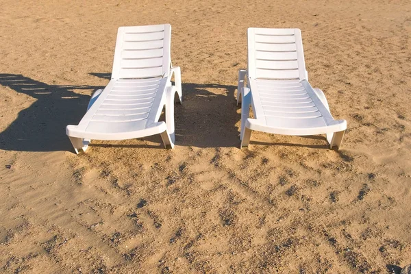 Yaz kum plajında iki sunlongers.