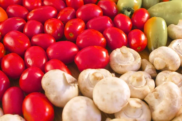 Свіжі овочі помідори, перець і гриби на кухонному столі . — стокове фото