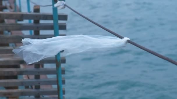 Plastic bag is tied to the cable of the sea pier. — Stock Video