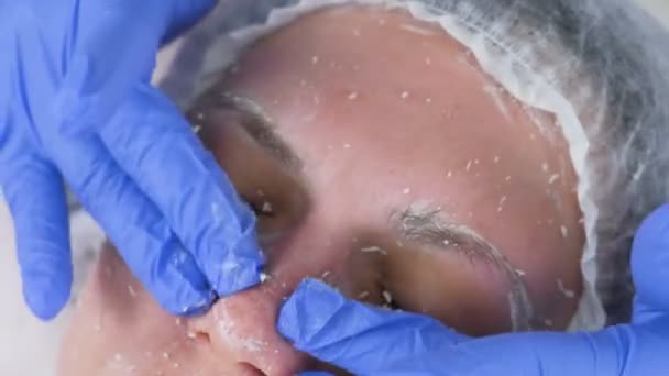 Schoonheidsspecialiste rolt het masker op het gezicht van de dames massage bewegingen. Schoonheidsspecialist gezichtsbehandeling. Close-up. — Stockvideo