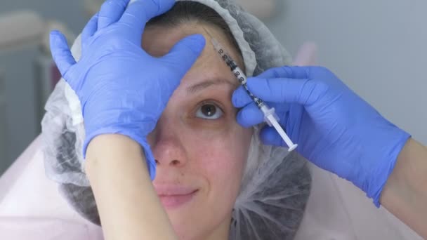 Contour kunststof gezicht. Verkwikkende gezichts injecties procedure voor aanscherping en gladstrijken van rimpels op de huid van het gezicht van een mooie jonge vrouw in een kliniek cosmetologie. — Stockvideo