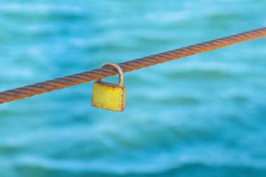Rusty Padlock demir tel deniz su arka plan üzerinde asılı.