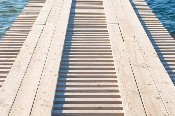 Wooden pier in the sea close-up with clear blue water under it. — Stock Photo, Image