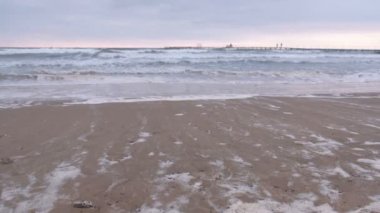 Büyük fırtınalı dalgalar deniz. İskele, kumlu plaj gün batımında güzel deniz manzarası.