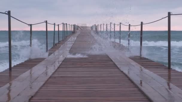 Onde schizza attraverso il molo di legno nel mare. Bellissimo paesaggio marino al tramonto . — Video Stock