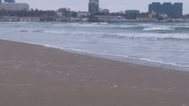 Büyük fırtınalı dalgalar deniz. Güzel deniz manzarası, kumlu plaj ve kıyı kenti gün batımında arka plan üzerinde.