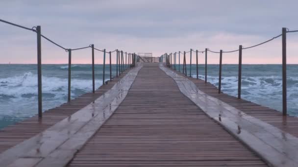Onde schizza attraverso il molo di legno nel mare. Bellissimo paesaggio marino al tramonto . — Video Stock