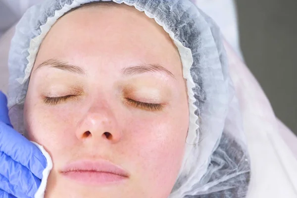 Косметолог вытирает лицо молодой женщины хлопковыми прокладками. Процедуры для лица . — стоковое фото