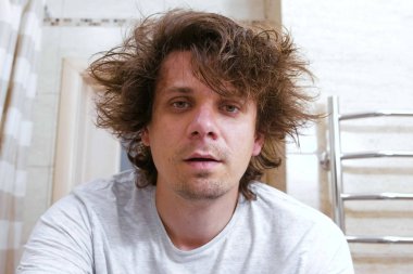 Sabahları banyo aynada Shaggy genç adam bakar.