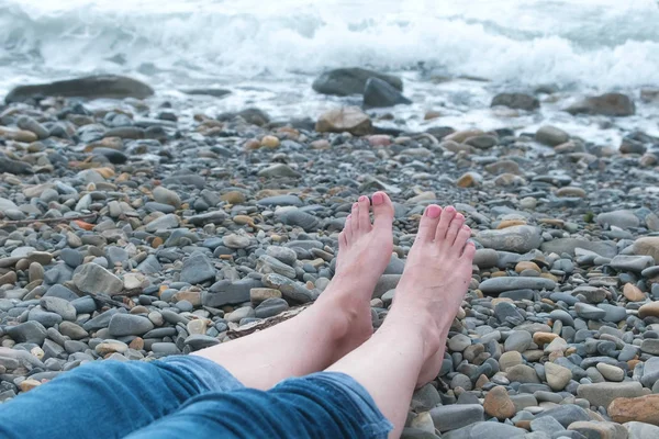 石のビーチで海に対してジーンズ レディース足. — ストック写真