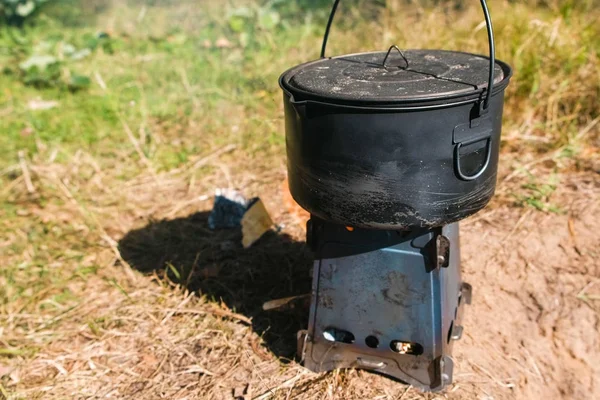 Pot on a metal camp furnace stove on woods outdoors. — Stock Photo, Image