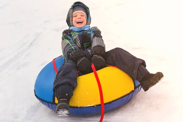 Bir boru karlı slaytta haddeleme bebeğim. Neşeli yakışıklı çocuk bir roller coaster binmek. — Stok fotoğraf