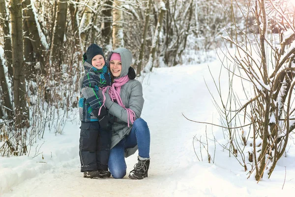 Счастливые улыбающиеся мать и сын обнимаются в зимнем лесу . — стоковое фото