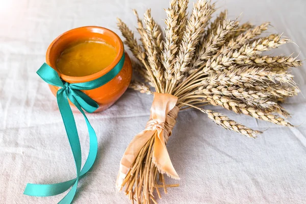 Pot of honey on linen cloth beside the dry oats plant. — Stock Photo, Image