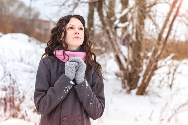 Красива молода жінка замерзла в зимовому лісі, теплі руки в рукавичках і моліться . — стокове фото