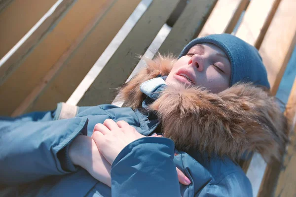 Зимой женщина заболела, лежала на скамейке в парке и тяжело дышала. . — стоковое фото