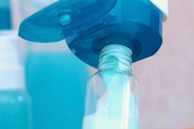 Büyük bir küçük şişe mavi şampuan dökün. Kavanoz dizi seyahat. Şişe yakın çekim.