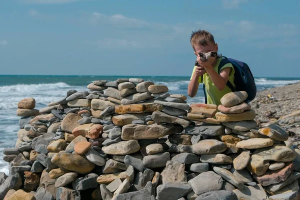 少年の再生、海海岸のビーチで石の要塞の後ろに隠れて. — ストック写真