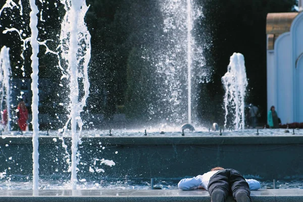 Pojken ser på fontänen i solig dag. — Stockfoto
