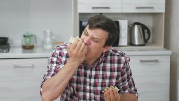 Omul flămând mănâncă shawarma pe bucătărie acasă, mănâncă repede acest lucru . — Videoclip de stoc
