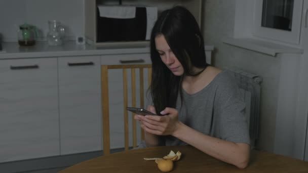 Одна молода жінка друкує повідомлення вночі на кухні . — стокове відео