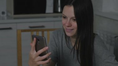 Geceleri mutfakta bir cep telefonu üzerinde korkunç bir video izlerken kadın.
