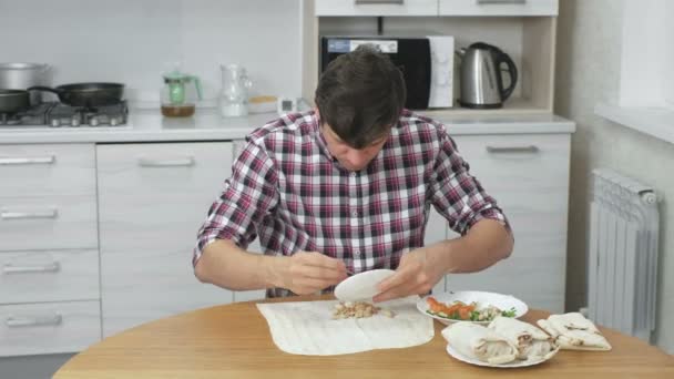 Homem com fome está cozinhando shawarma na mesa da cozinha em casa e rapidamente comer isso . — Vídeo de Stock