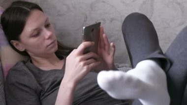 Kanepede yatan ve cep telefonu, bir şey okuma uykulu kadın.
