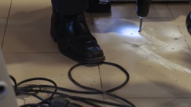 Ember fúrók a padlón egy fúróval, csempe a padlón. — Stock videók
