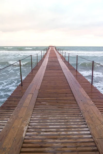 Wooden pier in the sea. Beautiful waves at sunset. — Stock Photo, Image