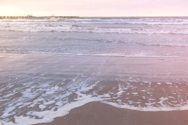 Golven in de zee. Prachtig zeegezicht met pier, zanderige strand bij zonsondergang. — Stockfoto