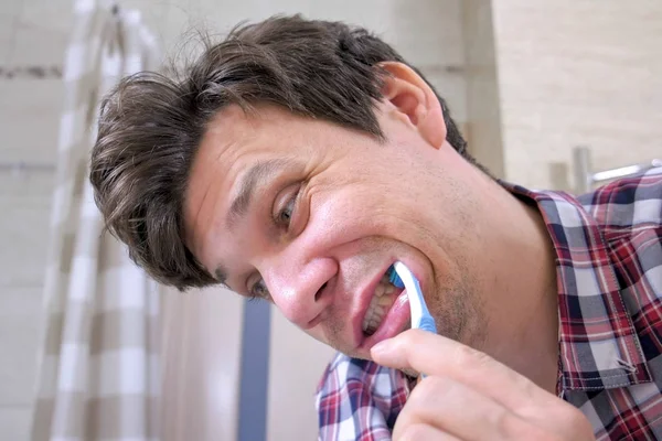 Verrückter junger Mann putzt seine Zähne im Badezimmer. — Stockfoto