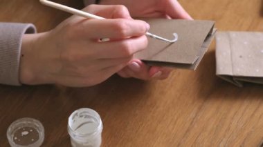 Kadın, çocuklar için Noel varış takvim yapar. Birkaç çanta üzerinde fırça ve beyaz boya ile yazar. Yakın çekim yakışıklı.