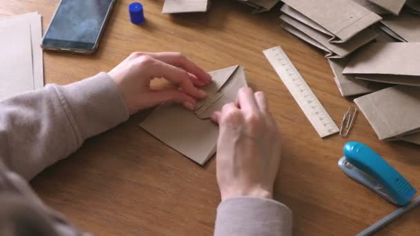 Nő tesz egy papír táskák-kraft papírból. Közeli kép: kezek. — Stock videók
