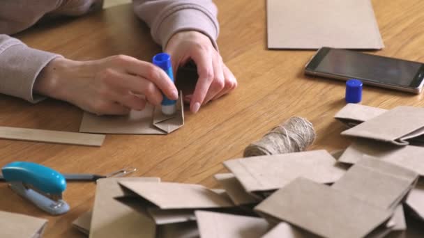 La donna fa dei sacchetti di carta di carta kraft per il calendario dell'avvento. Mani in alto. Incollare la carta . — Video Stock