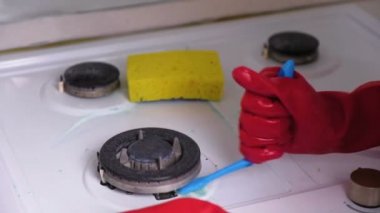 Kırmızı lastik eldiven yıkar kirli gaz sobası bir fırça ve sünger ile kadının eller.