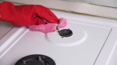 Kırmızı lastik eldiven yıkar kirli gaz sobası bir fırça ve sünger ile kadının eller.