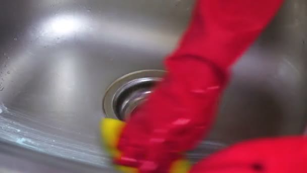 Frau wäscht in roten Handschuhen einen Metallhahn mit Schwamm in der Küche. Hände aus nächster Nähe. — Stockvideo