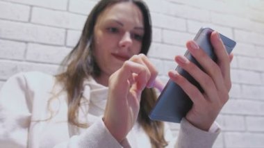 Gülümseyen kadın oturuyor ve biri kafede bekliyorum cep telefonunda bir mesaj yazarak.